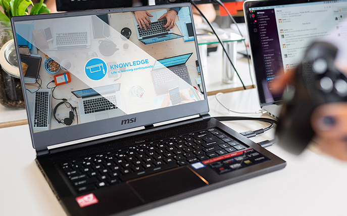 a learning management system loading onto a laptop screen in a busy office