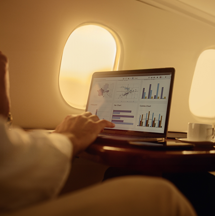 business person reviewing various different graphs and charts on their laptop mid flight on an aircraft